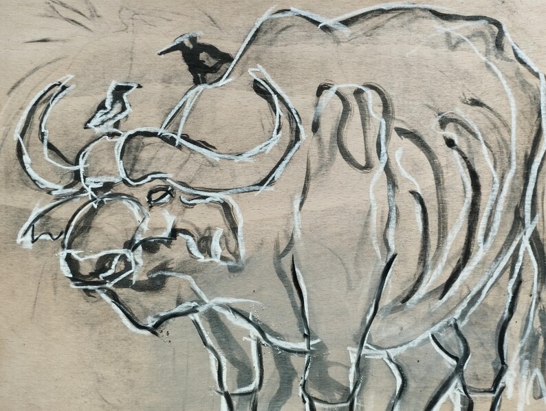 May include: A charcoal and white ink drawing on tan paper depicting a large buffalo with curved horns. Two small birds are perched on the buffalo's back and head. The artwork uses expressive, loose lines to define the animal's form and features.