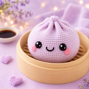 May include: A light purple crocheted dumpling toy with a rounded shape and a knotted top. The dumpling features two large black plastic safety eyes, a small embroidered black smile, and two pink crocheted circles on the cheeks for blush.