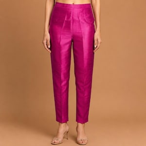 Könnte beinhalten: Hoch taillierte Hose in einem leuchtenden Magentaton mit geradem Schnitt und einem dezenten Glanz. Die Hose hat ein klares, maßgeschneidertes Erscheinungsbild mit einem strukturierten Bund und einer glatten Oberfläche bis zum Knöchel.