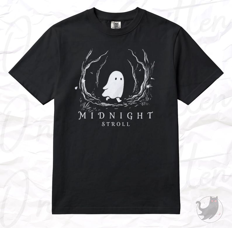Op de afbeelding: Een zwart t-shirt met korte mouwen en een witte afbeelding van een klein spookje dat door een gestileerd bos loopt. Onder de illustratie staat de tekst MIDNIGHT STROLL in witte hoofdletters. Het shirt heeft een ronde hals en een standaard pasvorm.