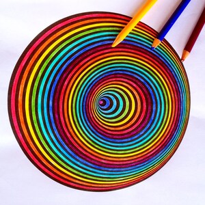 K&ouml;nnte beinhalten: Ein farbenfrohes Regenbogen-Spiralendesign, das mit Buntstiften auf wei&szlig;es Papier gezeichnet wurde. Die Stifte liegen neben der Spirale auf dem Papier.