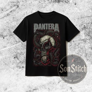 May include: A black short-sleeve t-shirt featuring a graphic print of a skull entwined with black snakes and red barbed wire. The word PANTERA is printed in large, distressed grey letters above the skull, with a circular logo below the skull.