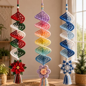 Puede incluir: Tres adornos de ganchillo en espiral para colgar. El de la izquierda es rojo, blanco y verde con una flor de pascua y borla. El central es un degradado arcoíris con flor y borla. El de la derecha es azul y blanco con un copo de nieve.