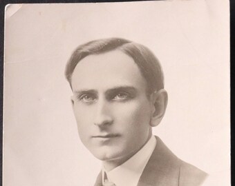 Può includere: Un ritratto in bianco e nero di un uomo in abito e cravatta. L'uomo guarda a sinistra della fotocamera. L'immagine è firmata "HARRY SOHNS".