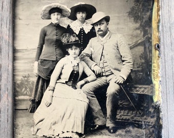 Könnte beinhalten: Ein Schwarzweiß-Foto aus der Zeit von vier Personen. Zwei Frauen tragen Hüte und Kleider. Ein Mann trägt einen Hut und einen Anzug. Eine Frau sitzt im Vordergrund und trägt einen Hut und ein Kleid.