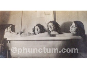 May include: Three people are relaxing in a bathtub, with their heads and shoulders above the water. The photo is in black and white and has a vintage feel.