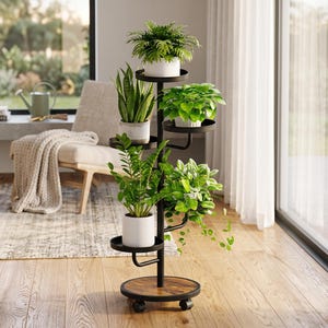 May include: A black metal plant stand with a circular wooden base and rolling casters, featuring five tiered shelves arranged in a spiral pattern. The stand holds five potted green plants in white containers at varying heights.