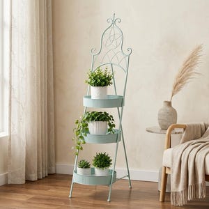May include: A light blue metal plant stand featuring three circular, ribbed shelves arranged vertically. The stand has a tall, arched decorative top with scrollwork details. Five small white pots containing various green plants sit on the shelves.