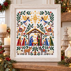 May include: A framed cross-stitch embroidery depicting a nativity scene with a central manger, figures of Mary, Joseph, and the infant, surrounded by angels, camels, wise men, sheep, and a donkey, all framed by green foliage and a golden star.