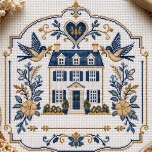 Puede incluir: Un patr&oacute;n de punto de cruz sobre tela blanca que presenta una casa central de dos pisos con contraventanas azules y una puerta oscura. El dise&ntilde;o est&aacute; enmarcado por dos p&aacute;jaros, arreglos florales y un motivo de coraz&oacute;n en tonos azul y oro.
