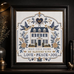 Puede incluir: Un bordado en punto de cruz enmarcado que presenta una ilustraci&oacute;n central de una casa flanqueada por dos p&aacute;jaros, motivos florales y un coraz&oacute;n en la parte superior. El texto dice: MAY THIS HOME BE BLESSED WITH LOVE PEACE JOY. Hilo azul marino, dorado y blanco.