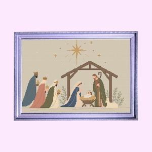 May include: A framed cross-stitch embroidery depicting a nativity scene with three figures bearing gifts, a central stable structure, a manger with a child, and a large star above, all rendered in muted earth tones within a silver frame.
