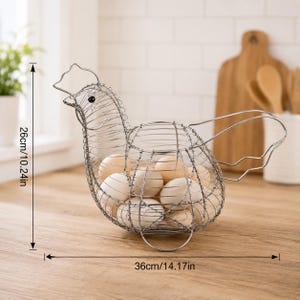 May include: A silver-colored wire egg basket shaped like a chicken, containing several light-colored eggs. The basket features a wire frame with a height of 10.24 inches and a width of 14.17 inches, as indicated by the visible measurement lines.