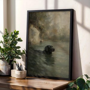 Può includere: Una stampa d'arte incorniciata che raffigura un dipinto a olio di un cane nero che nuota in uno specchio d'acqua calmo dai toni verde spento. L'opera è racchiusa in una semplice cornice nera e mostra un paesaggio sereno con pennellate morbide.