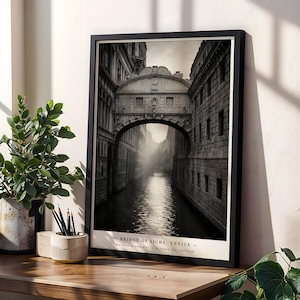 May include: A framed black and white wall art print depicting the Bridge of Sighs in Venice, featuring a stone archway over a canal. The print includes the text BRIDGE OF SIGHHS, VENICE and MAGNAVISIOPRINTS - CLASSIC COLLECTION at the bottom.