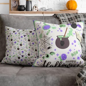 May include: Two square throw pillows featuring a white background with a repeating Halloween pattern. The design includes purple cauldrons, green potions, spiderwebs, spiders, eyeballs, bats, and spellbooks, with the text Happy Halloween.