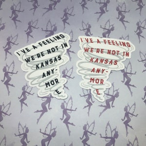 May include: Two white stickers with a tornado design. The stickers have the text "I've a feeling we're not in Kansas anymore" in black text.