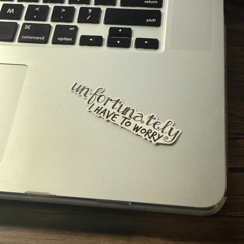 Pu&ograve; includere: Un adesivo bianco e nero con il testo "purtroppo devo preoccuparmi" su un laptop argentato.