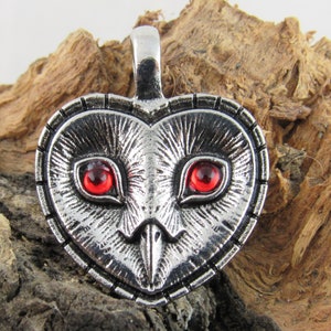 Peut inclure: Pendentif en forme de c&oelig;ur en argent avec un motif de hibou et des yeux en pierres pr&eacute;cieuses rouges.