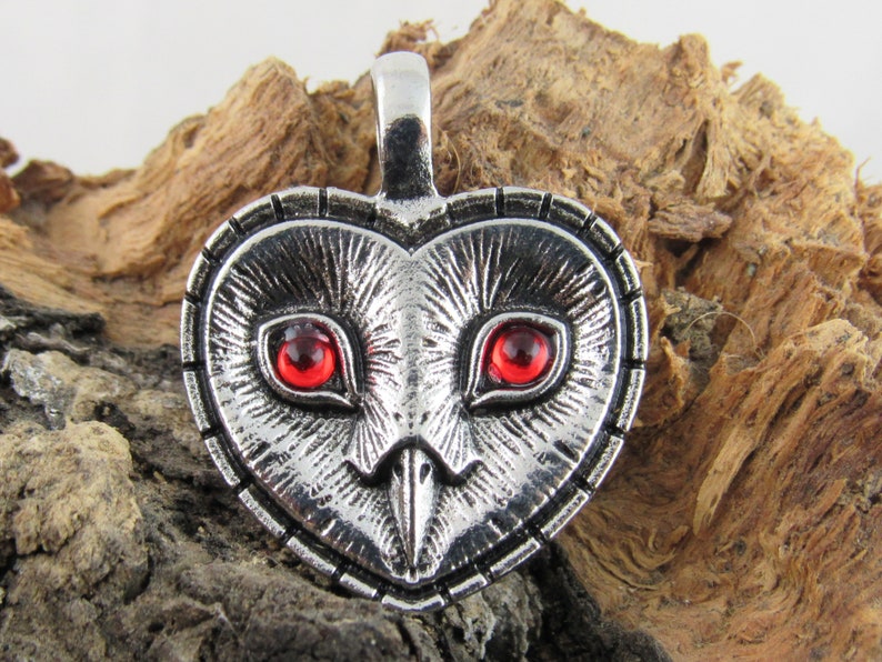 Peut inclure: Pendentif en forme de c&oelig;ur en argent avec un motif de hibou et des yeux en pierres pr&eacute;cieuses rouges.