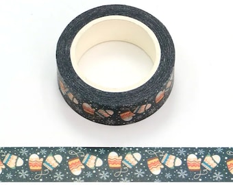 May include: A roll of washi tape with a dark blue background and a repeating pattern of white snowflakes and orange and brown mittens.