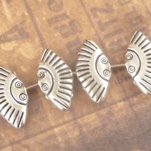 May include: Four silver metal fan-shaped beads with a decorative design. The beads are strung on a wire.