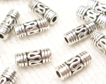 May include: Silver metal beads with a decorative design. The beads are cylindrical and have a smooth, polished finish.