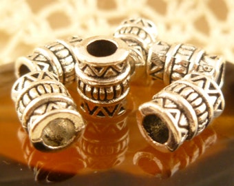 May include: Six silver metal beads with a geometric pattern. The beads are cylindrical and have a smooth, polished finish.