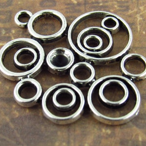 May include: Silver metal charm with a design of overlapping circles. The charm has a rustic, antique look.