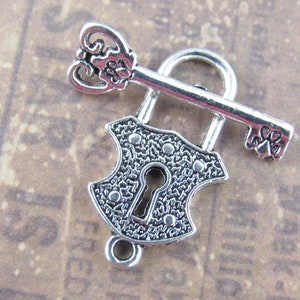 May include: Silver-toned lock and key charm with an ornate design. The lock has a keyhole and the key has a decorative handle.