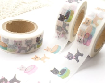 May include: Two rolls of white washi tape with a repeating pattern of cute cartoon cats and bowls. The cats are in various colors, including gray, black, white, and orange.