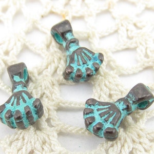 May include: Three small, antique-looking metal charms in the shape of a hand with five fingers. The charms are a dark bronze color with a turquoise patina.
