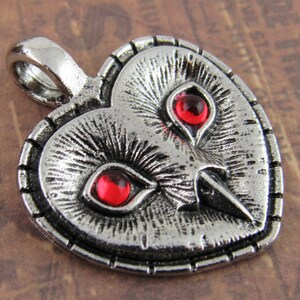 Peut inclure: Pendentif en forme de c&oelig;ur en argent avec un motif de hibou et des yeux en pierres pr&eacute;cieuses rouges.