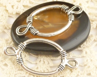 May include: Two silver oval-shaped clasps with a twisted wire design. The clasps are on a brown and black background.