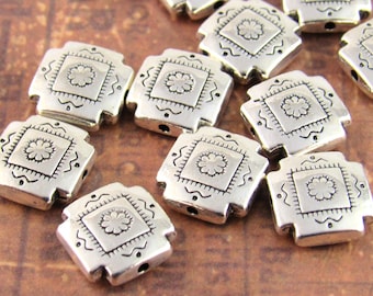 May include: A collection of square silver-toned metal beads, each featuring a central embossed flower design within a square border, accented by small dots and wavy lines along the edges, with a hole visible on the side of each individual bead.