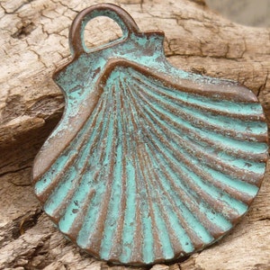 May include: A teal green metal seashell charm with a loop at the top for hanging. The seashell has a detailed, textured surface.