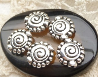 May include: Five silver metal beads with a spiral design. Each bead has a raised edge with small round bumps.