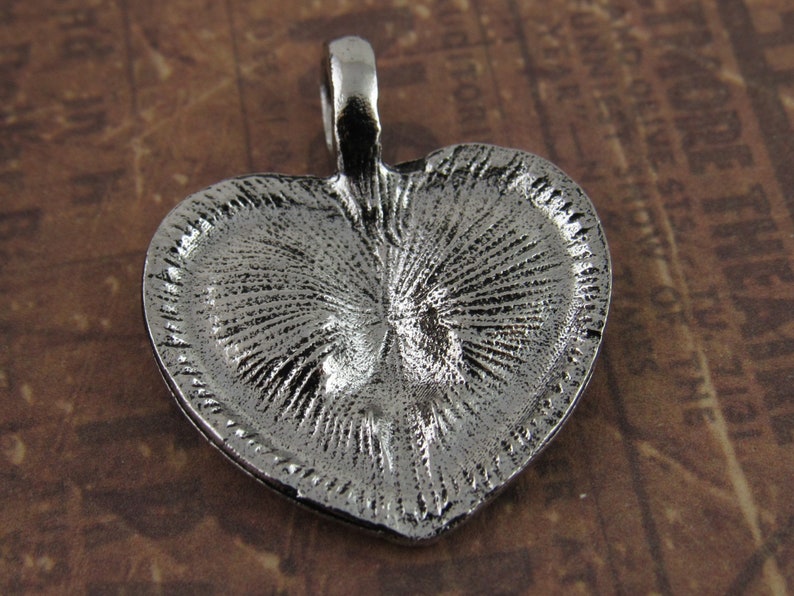 Peut inclure: Pendentif en forme de c&oelig;ur en argent avec un design textur&eacute;. Le pendentif a une boucle en haut pour l'attacher &agrave; une cha&icirc;ne.