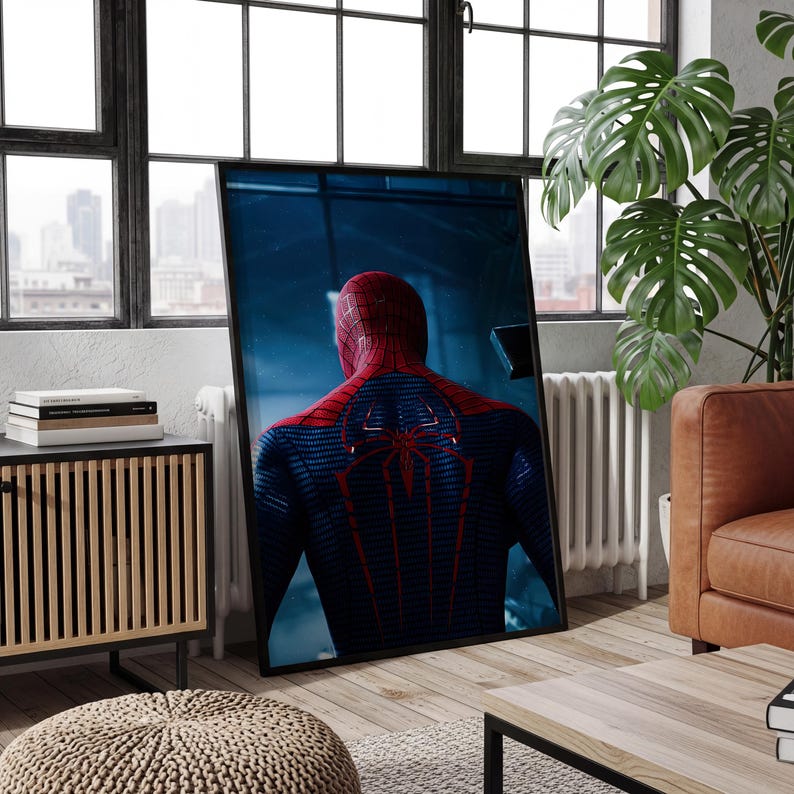 May include: A framed rectangular wall art print featuring a rear view of a superhero character in a textured blue and red suit with a prominent red spider emblem on the back, set against a dark, moody, and atmospheric blue background.