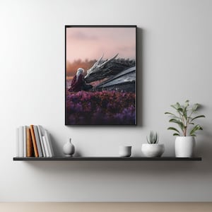 Puede incluir: Un cuadro decorativo enmarcado que muestra a una persona de pelo largo blanco con una capa roja oscura, sentada en un campo de flores moradas frente a un gran dragón gris oscuro texturizado. La escena se sitúa bajo un cielo suave y brumoso.