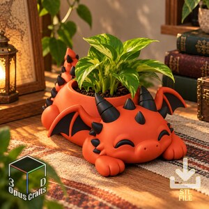 May include: A bright orange dragon-shaped planter with black horns, spikes, and wing accents. The dragon has a smiling expression with closed eyes and holds a green leafy plant in its back. The base features a 3D Opus Crafts logo and a download icon.