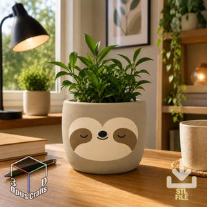 Puede incluir: Una maceta cilíndrica de color gris claro con una cara de perezoso estilizada con ojos cerrados y una pequeña nariz negra. La maceta contiene una planta verde y se asienta sobre una superficie de madera. El texto 3D Opus Crafts y STL FILE es visible.