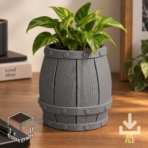 Peut inclure: Un pot de fleurs gris en forme de tonneau avec une texture de grain de bois et des bandes horizontales ornées de détails de rivets circulaires. Une plante pothos panachée verte et jaune est plantée à l'intérieur du récipient.