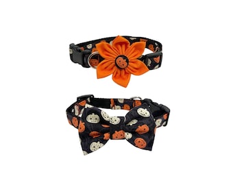 May include: Two black pet collars featuring a pumpkin pattern in orange and white. One collar includes a large orange fabric flower with a central pumpkin button, while the other collar features a matching fabric bow tie with a pumpkin print.
