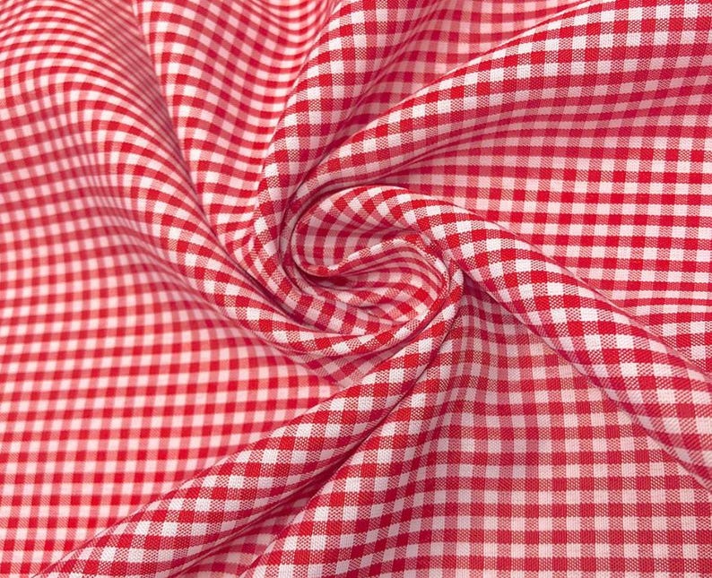 K&ouml;nnte beinhalten: Rotes und wei&szlig;es Gingham-Gewebe mit einem karierten Muster. Der Stoff ist gefaltet und drapiert und zeigt die Textur und die Webart.