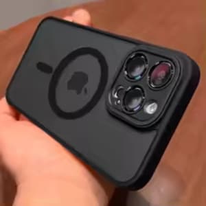 May include: A matte black smartphone case featuring a circular magnetic charging ring on the back and a raised square camera module cutout. The case has a smooth finish and includes a prominent Apple logo visible through the center of the ring.