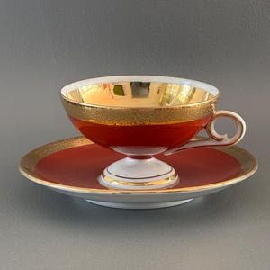 Bremer Schmidt EisenbergKopp och fat i fint porslin i vintagestil med rika gyllene-röd-orange nyanser, guldkant och guldfärgad insida