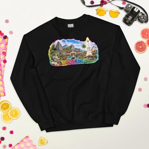 Könnte beinhalten: Ein schwarzes Langarm-Sweatshirt mit einem farbenfrohen Grafikdruck von Yogyakarta, Indonesien. Das Design zeigt eine Landschaft mit Tempeln, Palmen, einem Vulkan und dem Schriftzug YOGYAKARTA in fetten, bunten Buchstaben am unteren Rand.