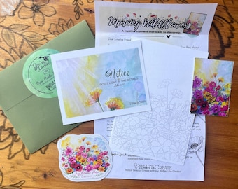 May include: A stationery set including a green envelope with a circular sticker, a watercolour card with the text Notice God's Light in the Details, a floral colouring sheet, a small wildflower print, and a sticker reading Joy Blooms Here.