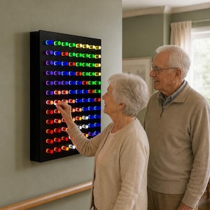 May include: A rectangular black wall-mounted board featuring a grid of illuminated cylindrical pegs in various colours including red, blue, green, and white. The pegs are arranged in horizontal rows and vertical columns, creating a glowing light display.
